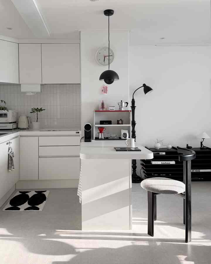 White and black kitchen space featuring a simple modern style counter and lighting arranged in a bright, clean atmosphere