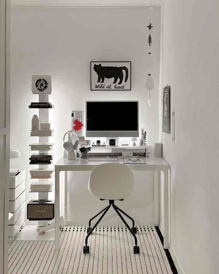 Simple modern home office space in white and black tones featuring a desk, chair, and computer centrally arranged
