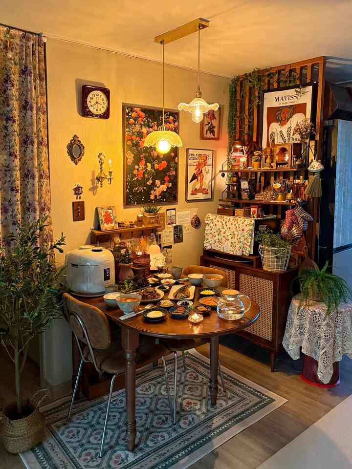 温かみのあるナチュラルカラーのダイニングルーム、木製テーブルと花柄カーテン、壁のアートとペンダントライトが印象的な空間を演出している