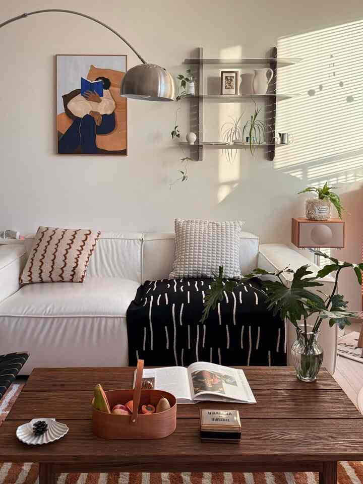 白と茶色の色調のリビング、ソファと木製のテーブル、フロアランプと植物が配置された雰囲気のあるインテリア
