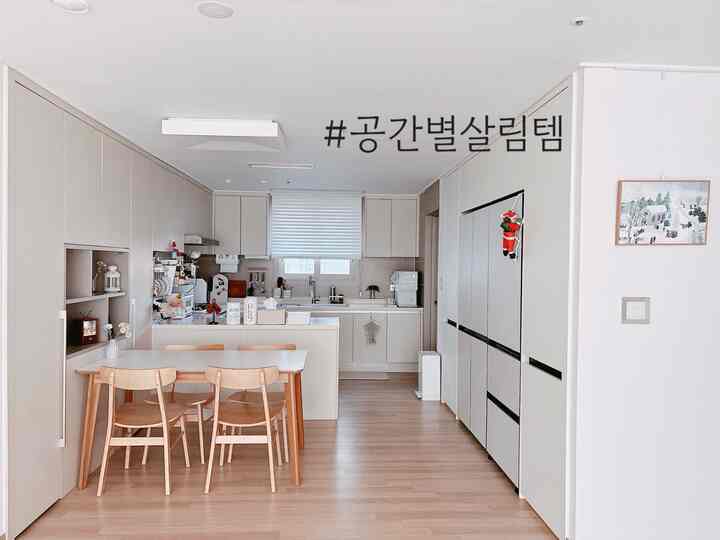 明るいベージュ色調のキッチン、4人用のナチュラルな木製ダイニングテーブルが配置された清潔感のある空間