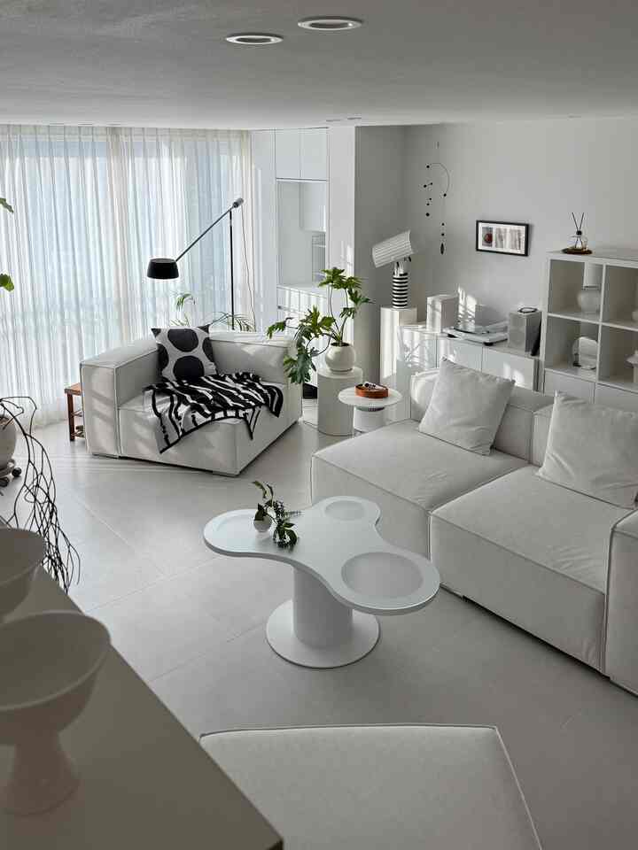 明るいホワイト調のリビング、モジュラーソファとユニークな形のソファテーブルが配置された清潔でミニマルなインテリア