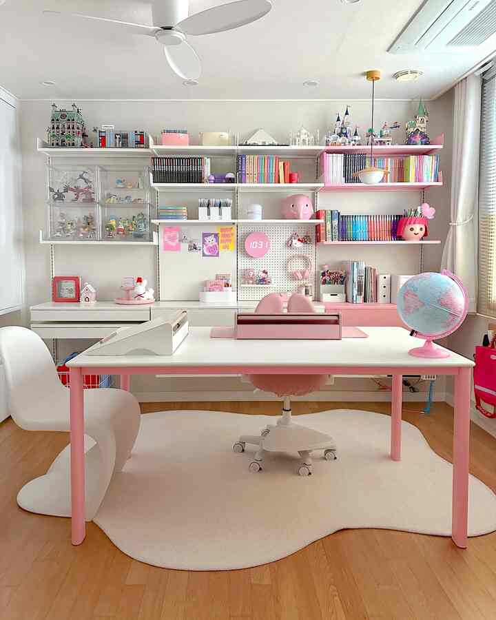 Pastel pink and white kids' study room featuring a large desk and organized bookshelf with a clean, simple look