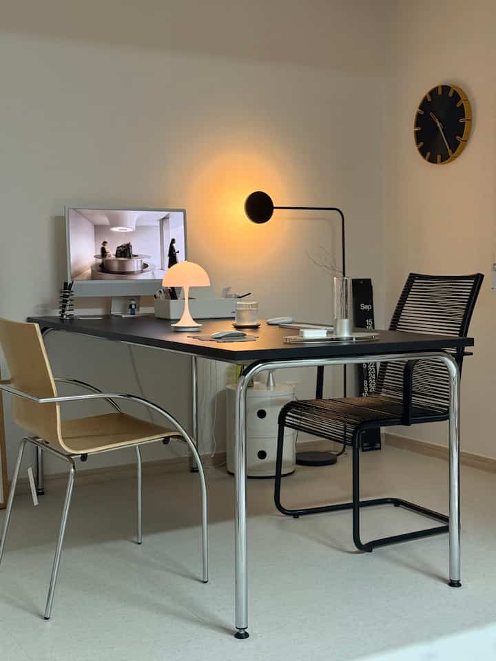 ホワイトとブラックのトーンのホームオフィス空間、モダンなデスクと椅子が配置されたすっきりとした作業スペース