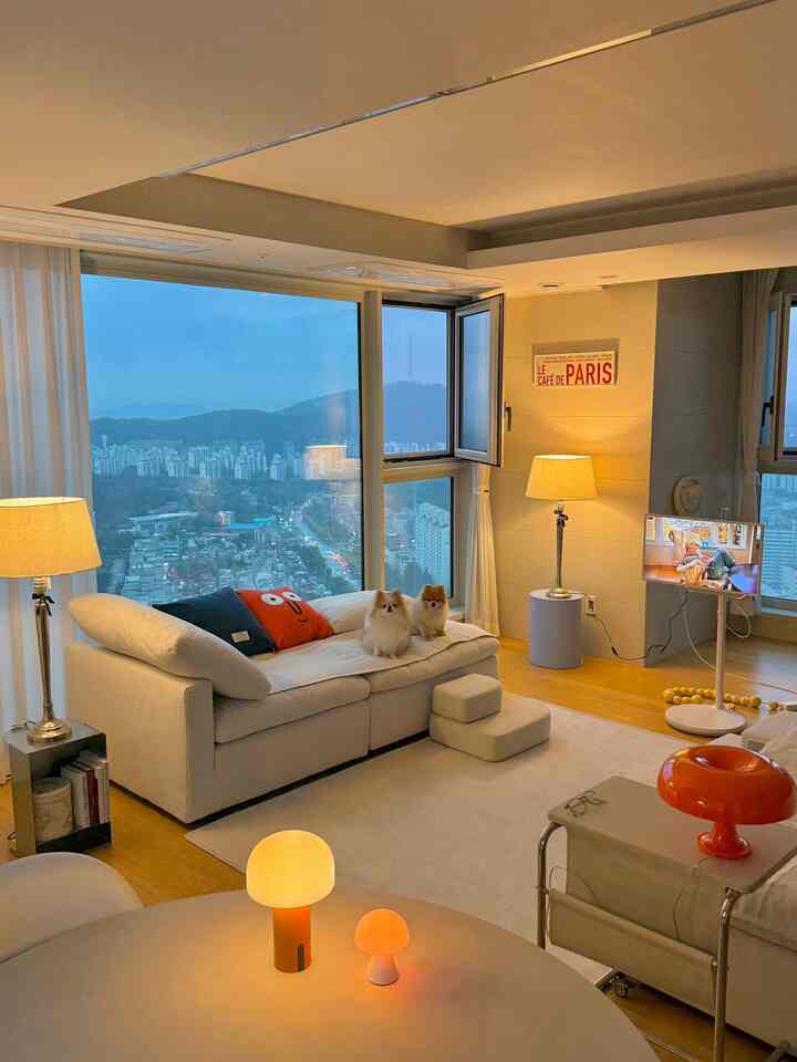 ホワイトとブラウンの色調のリビング、中央のソファの上に犬が二匹とテーブルランプが配置されたミッドセンチュリーモダンな雰囲気のインテリア