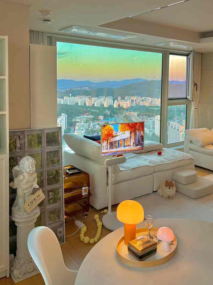 白と自然な木目調が調和した4人用リビング、大型ソファとペットステップ、小さな犬がいる落ち着いた雰囲気の空間