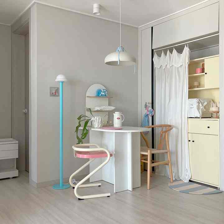 白を基調としたミッドセンチュリーモダンのダイニング、青い照明とナチュラルな椅子が映える印象的な空間