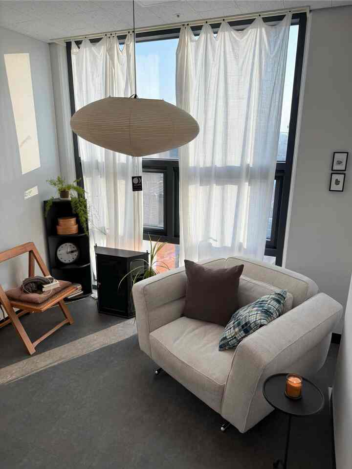 White and natural tone living room featuring a single sofa and wooden chair in a simple and cozy space