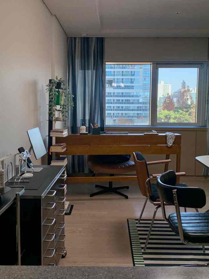 Wood tone and black-themed home office featuring a large window with long curtains, practical and compact study area