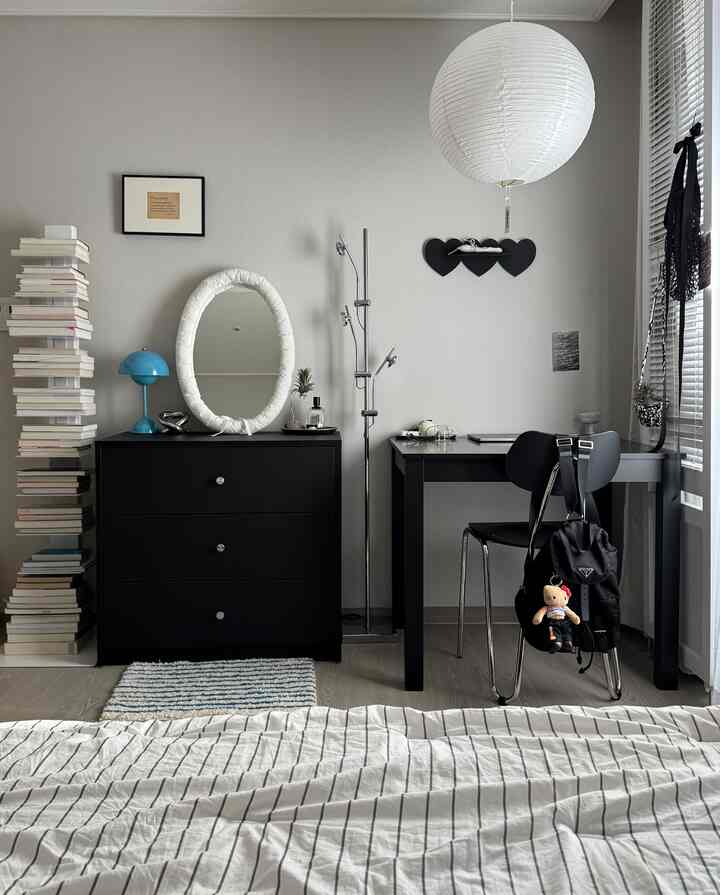 白と黒のシンプルな寝室、チェストとデスク、ベッドカバーが配置された清潔感のある雰囲気のインテリア