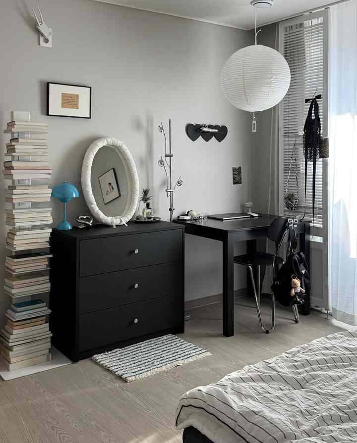 明るい木目調の床と白い壁、黒い家具、丸いペンダントライトが配置された北欧風の寝室の印象的な空間