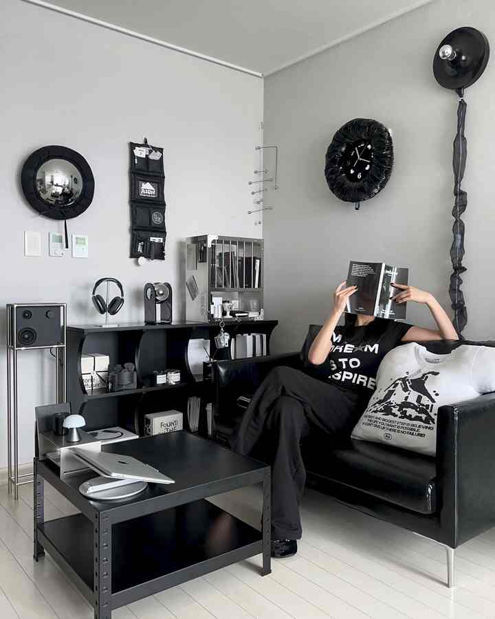 Modern black-themed living room featuring black leather sofa and metal coffee table in a minimalist setting