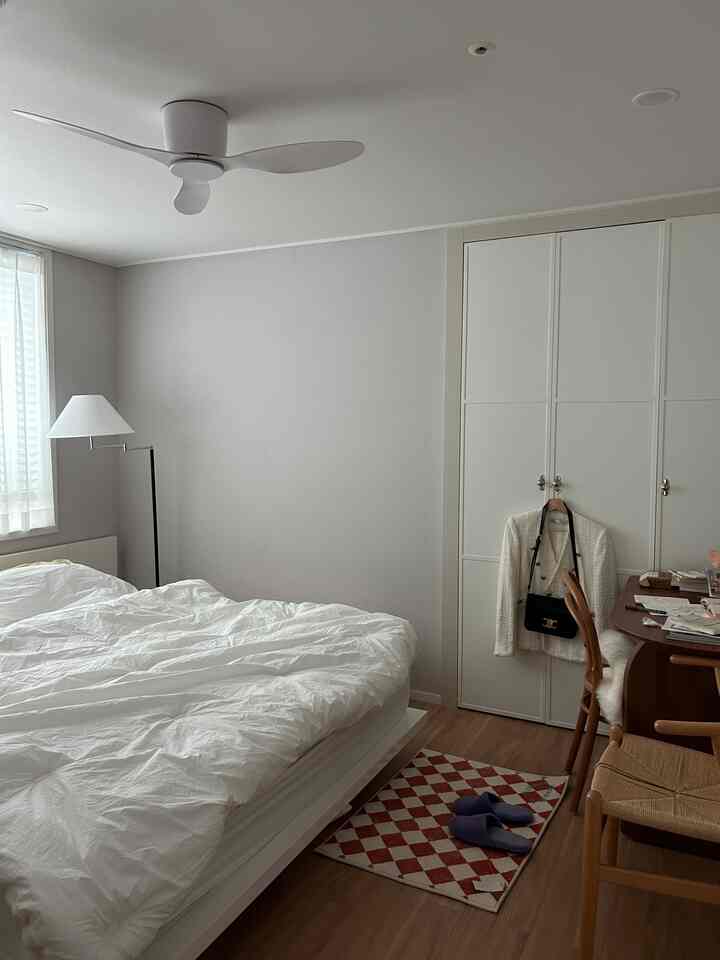 White and brown toned bedroom featuring a bed, desk, and argyle rug creating a clean and natural atmosphere