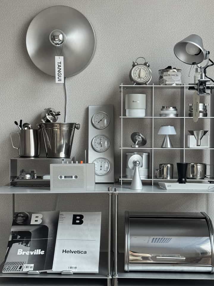 Silver-toned kitchen space featuring stainless steel storage shelves neatly organized with various kitchen utensils, showcasing a modern interior