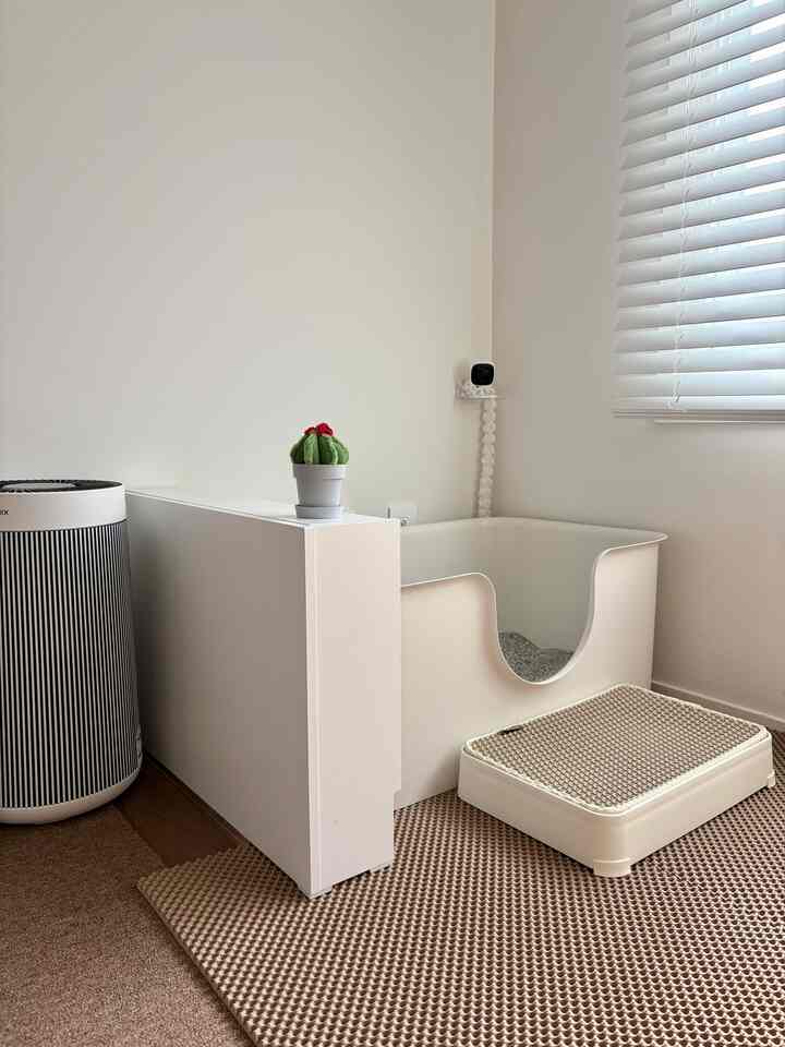 明るいホワイトとベージュ調の空間にキャットトイレとペットステップが配置された清潔感のあるリビングインテリア