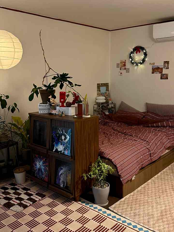 Vintage-toned bedroom with dresser, plants, and cozy Christmas decorations creating a warm atmosphere