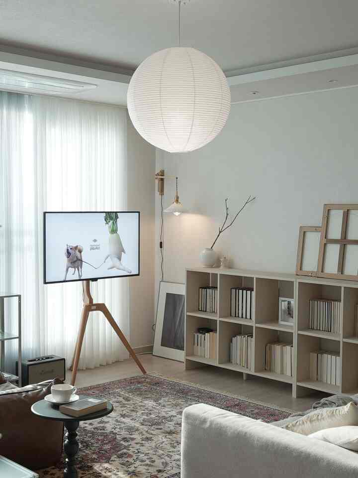 明るくナチュラルな色調のリビングルーム、北欧スタイルのソファと本棚が配置された雰囲気のある空間