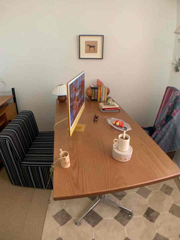 温かみのある木目調のホームオフィス、黄色いモニター、デスク、本棚とソファが配置されたシンプルモダンな雰囲気の空間