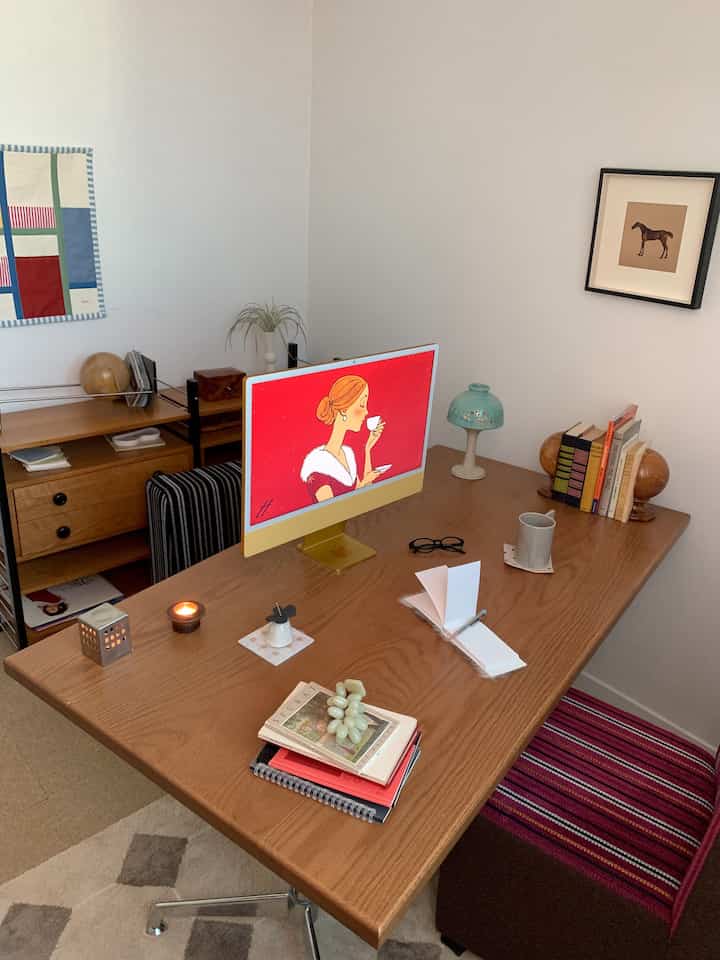 Natural brown toned study space featuring a large wooden desk and wall art in a cozy home office