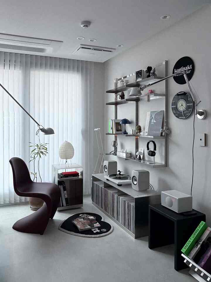 White and dark brown toned living room featuring a unique armchair, storage shelves, and audio equipment in a minimal interior