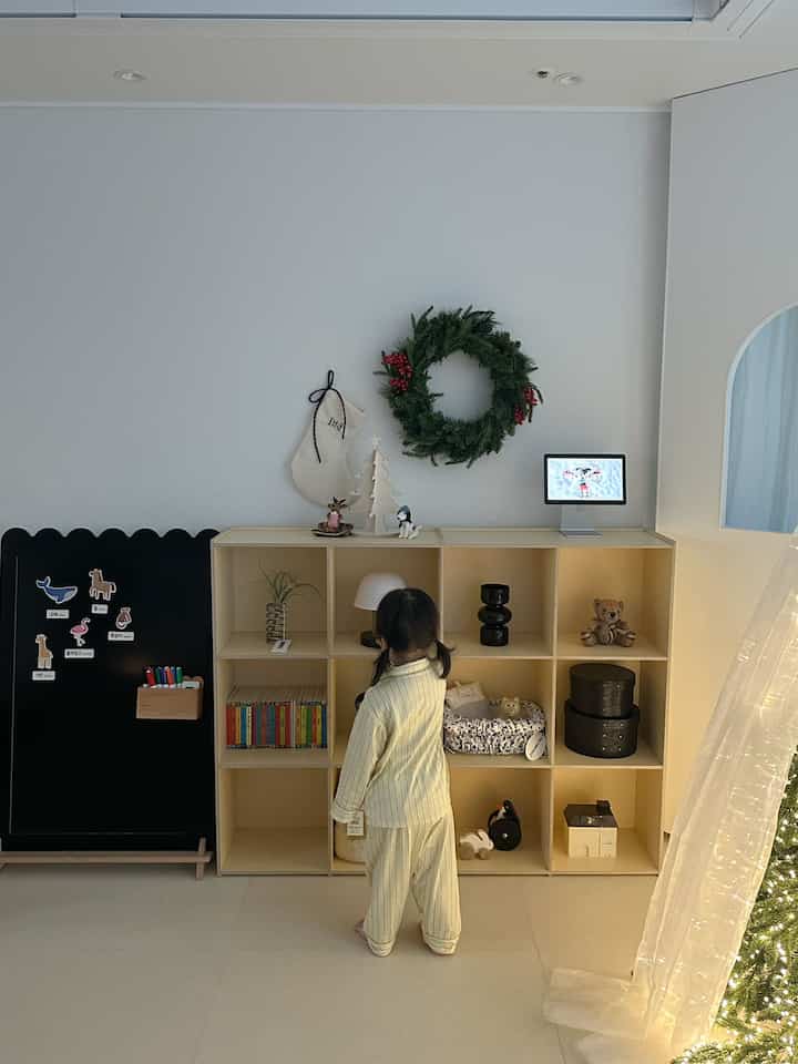 白とベージュの色調の子供部屋、本棚と子供が配置された温かみのあるインテリア