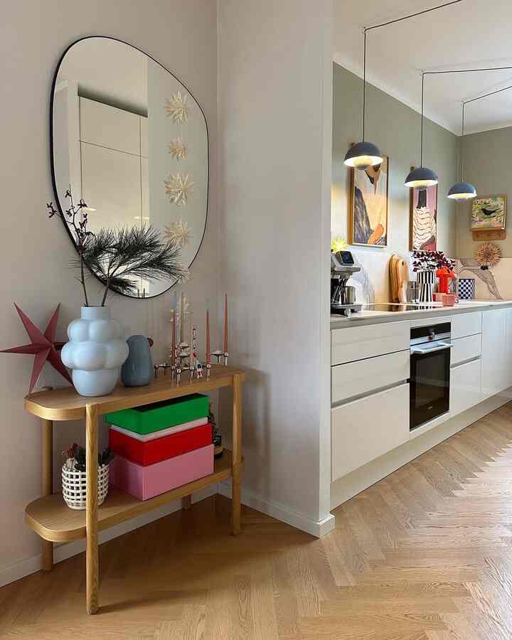 Cozy natural Scandinavian kitchen with natural wood flooring and white cabinets accented by festive decor