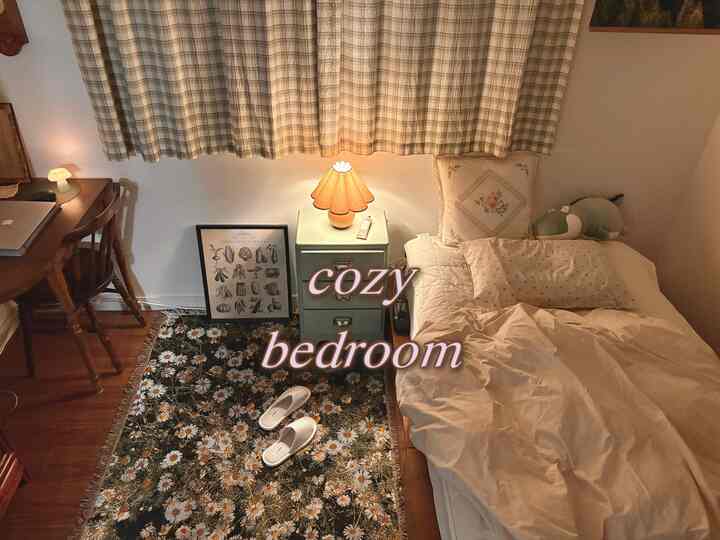 黄色い照明とデイジーパターンのラグが置かれた、木製家具とベージュの寝具を備えた雰囲気のある寝室