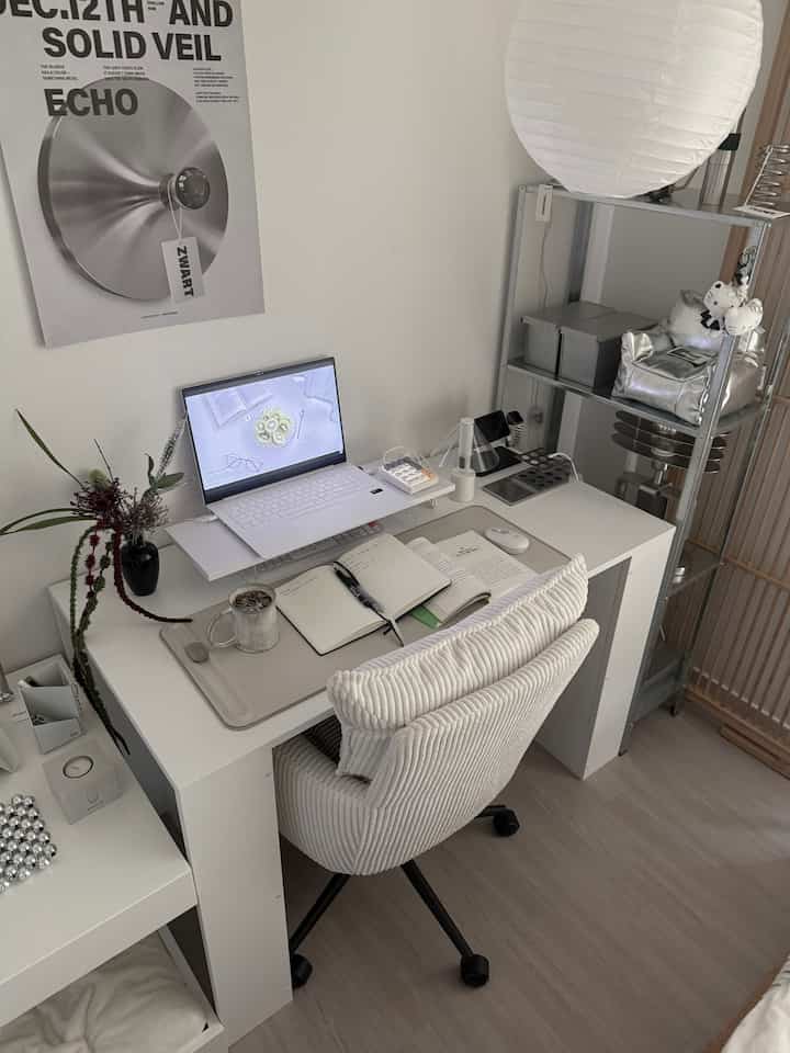 ホワイトとシルバーのトーンが特徴のホームオフィス、白いデスクと椅子、ノートパソコンとラックが配置されたすっきりとした作業空間