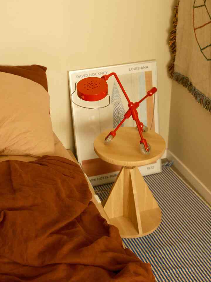 Warm wood tone bedroom featuring brown bedding and a red vintage table lamp on a wooden stool, creating a cozy atmosphere