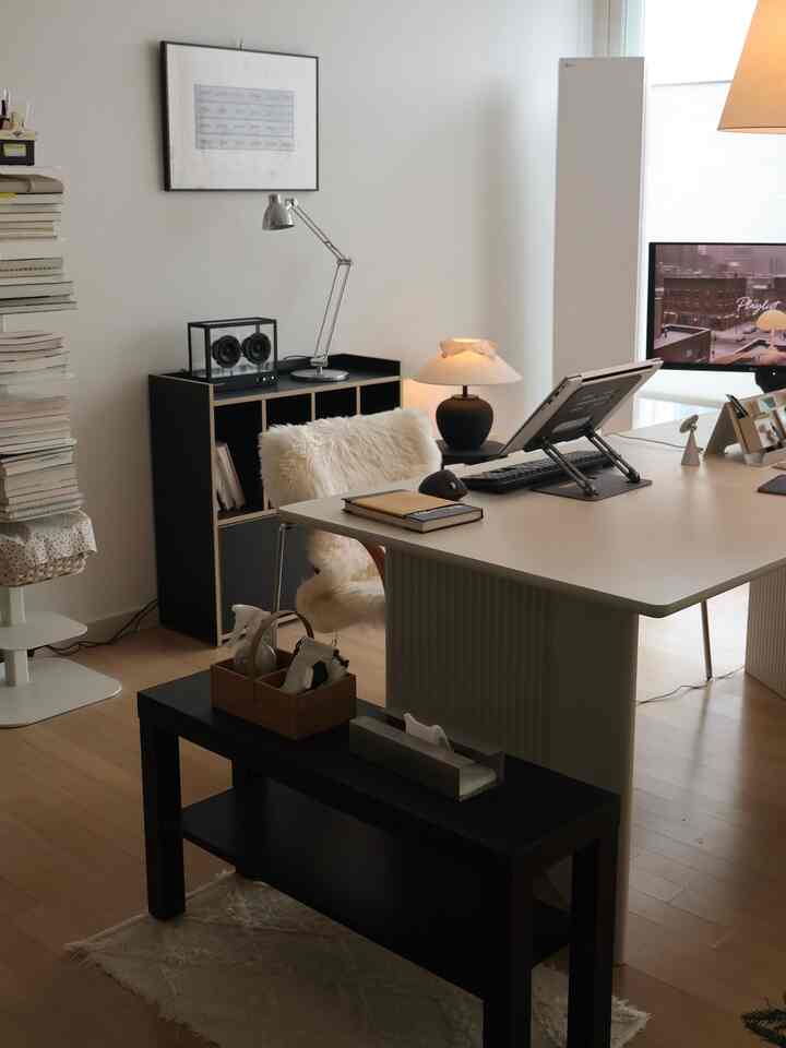 Bright white and natural wood tone living room study, featuring a clean desk and ambient lighting creating a modern workspace