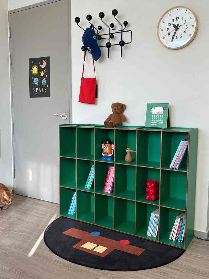 緑色を基調とした子供部屋、整頓されたキューブ収納とおもちゃ、壁時計が配置されたモダンな空間