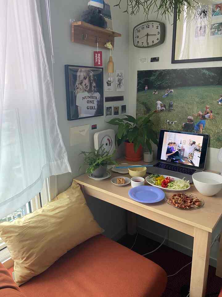 ナチュラルな木目調とオレンジ色の一人用ソファがあるコンパクトな一人暮らしの木製デスク空間