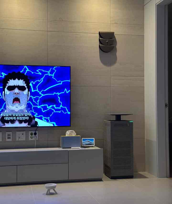 グレーとホワイトの色調のリビング、壁掛けテレビとテレビ台、壁時計が配置された落ち着いたモダンな空間