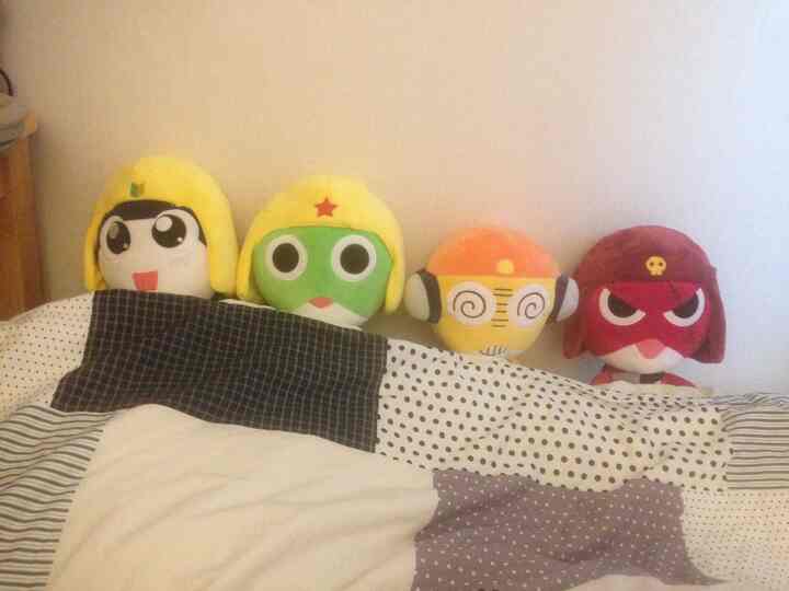 パターンの掛け布団の上に黄色いヘルメットをかぶったかわいいキャラクターのぬいぐるみが並ぶ、居心地の良い寝室のインテリア