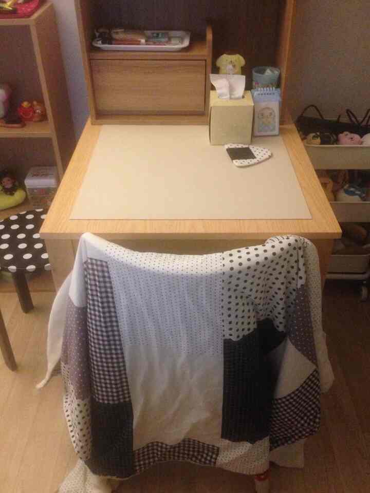 ナチュラルな木目調のテーブルとチェック柄とドット柄のパッチワークブランケットが配置された、雰囲気のあるダイニングルーム