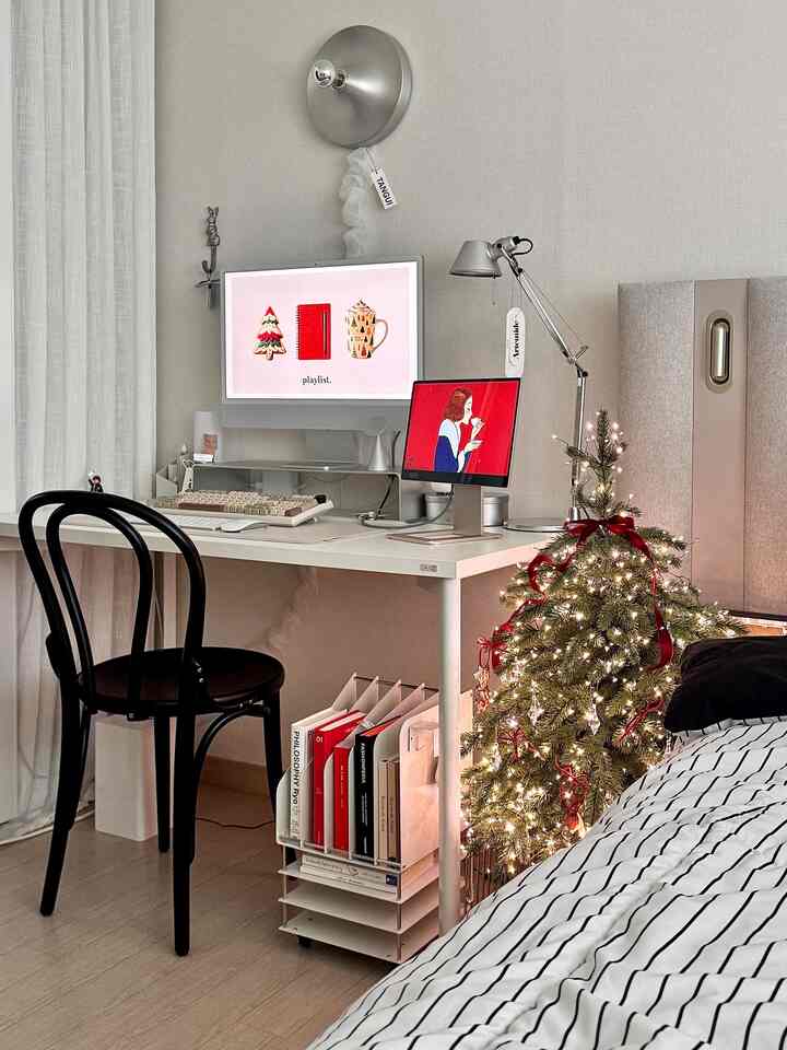白とシルバーの色調の寝室に、デスクやコンピューター、飾られたミニクリスマスツリーが配置された雰囲気のあるインテリア