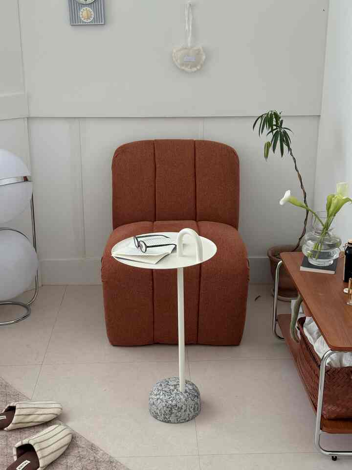 白と茶色のトーンのリビング、茶色のアームチェアと白いサイドテーブルが配置された自然な雰囲気のインテリア