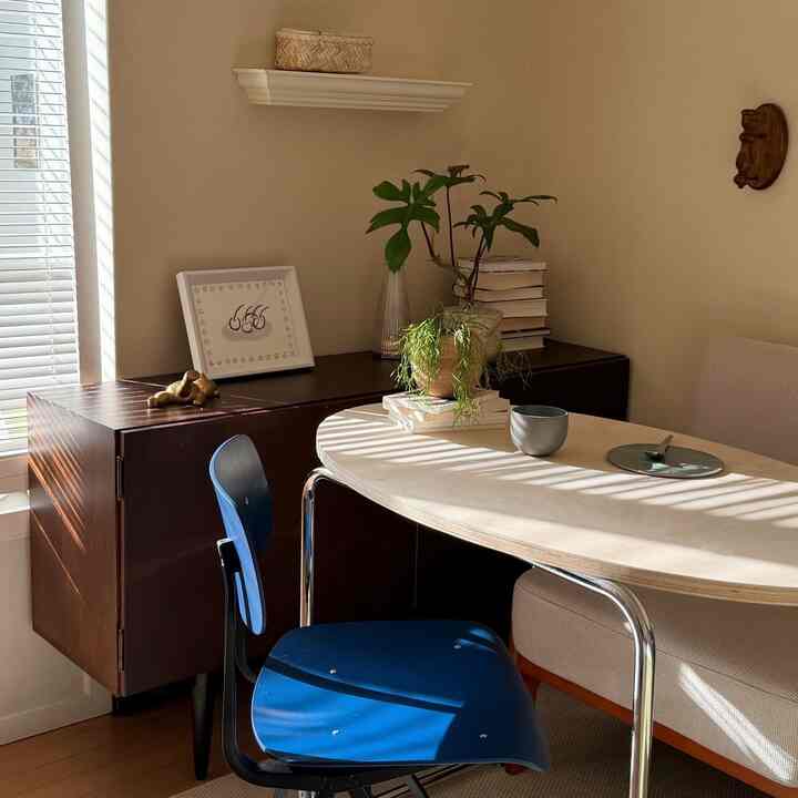 ベージュとブラウンの色調のダイニング、青いダイニングチェアと植物が配置された自然なモダンな空間