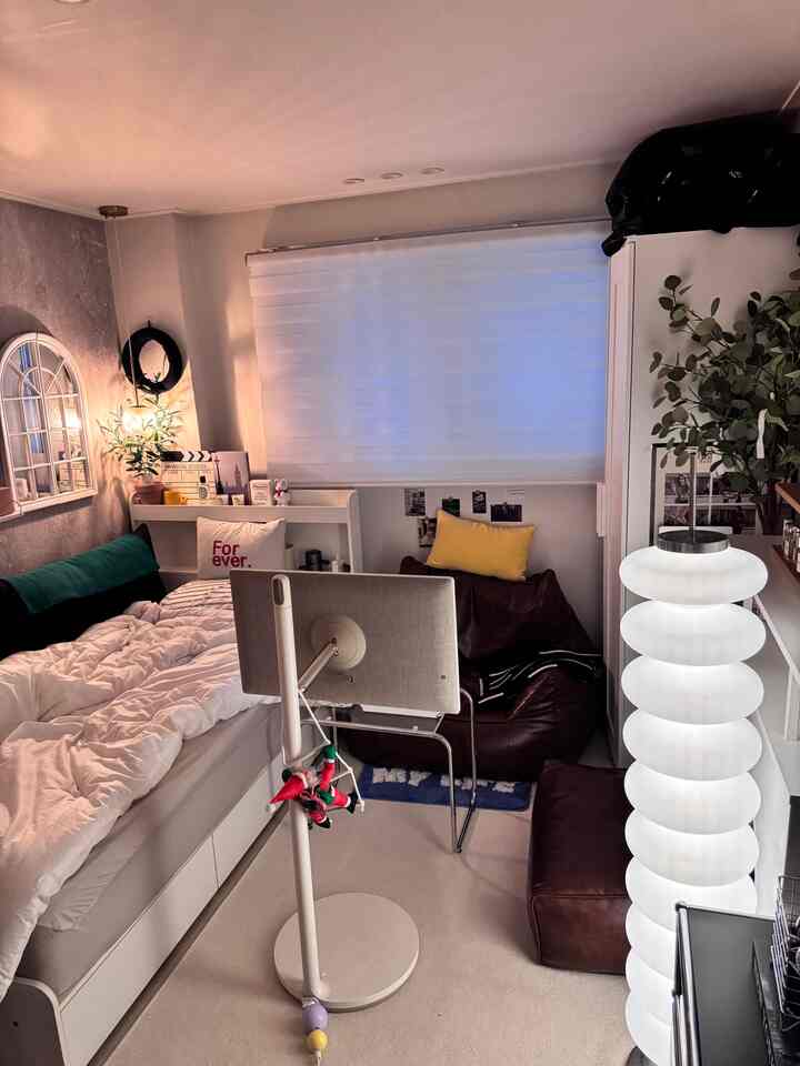 ホワイトとベージュの色調の狭いワンルーム、コンピュータモニターとビーンバッグソファが配置された雰囲気のあるインテリア