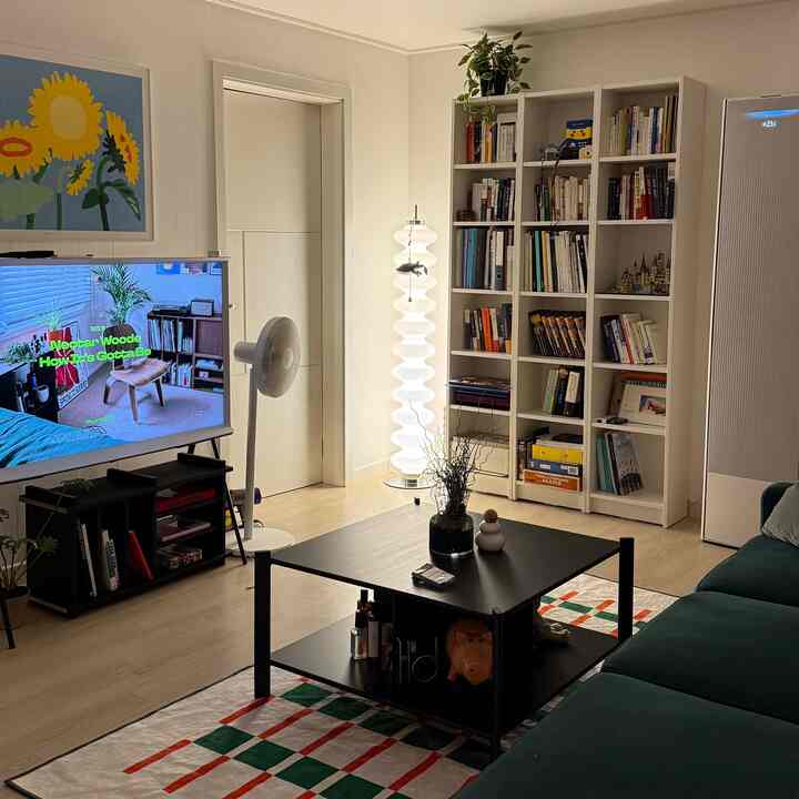 白と黒のトーンのリビング、大きな本棚と黒いコーヒーテーブル、深緑のソファが落ち着いた雰囲気を醸し出す空間