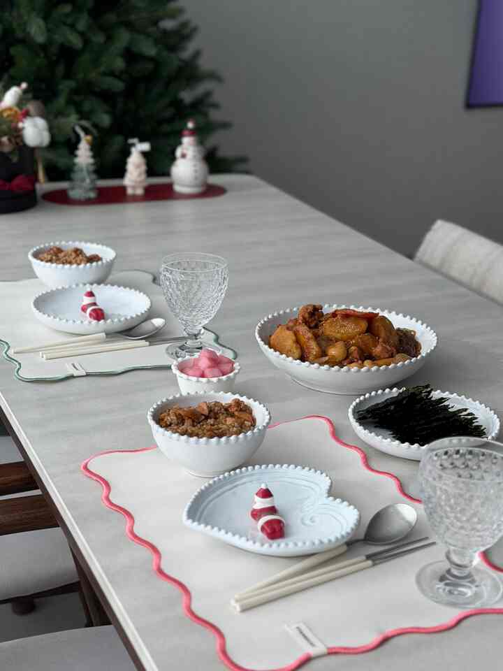 白を基調としたダイニングテーブル、モダンで清潔感のある印象的な空間に二人分の食卓とサンタのクリスマス小物が配置されている