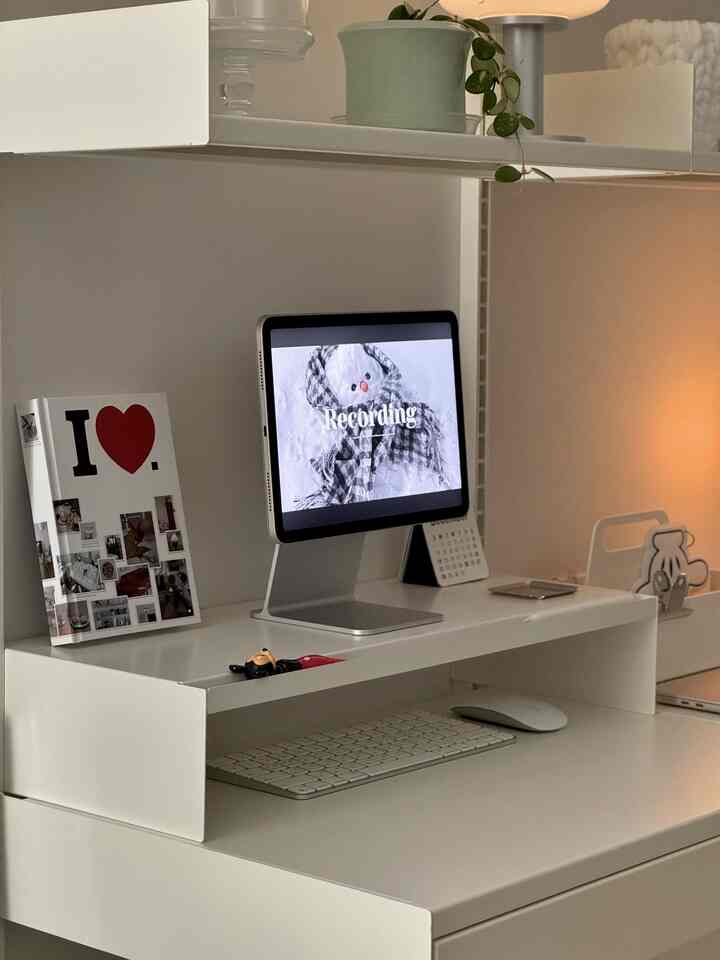 White-toned compact home office featuring a minimal desk and monitor stand in a clean setup