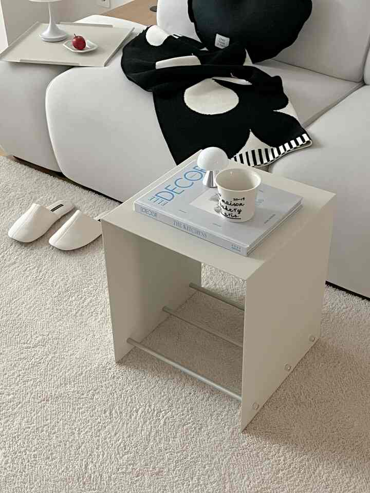 Bright cream tone rug with white side table and sofa in a simple, natural living room setting