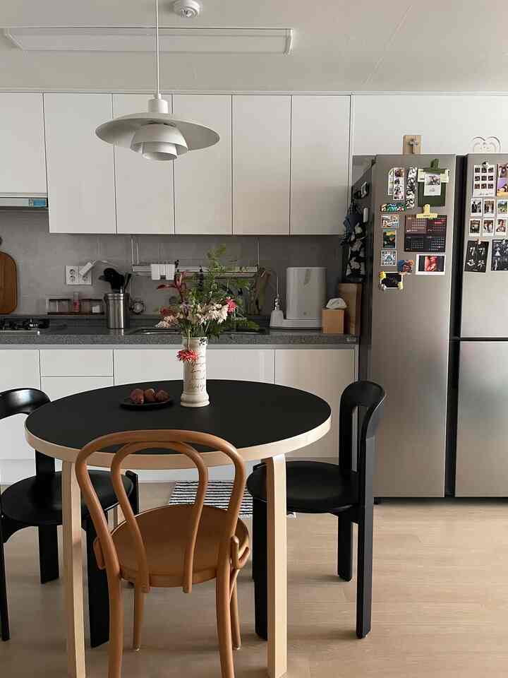 白と黒のトーンのキッチン、木製のダイニングテーブルとトーンチェア、ペンダントライトが配置されたモダンでナチュラルな雰囲気のインテリア