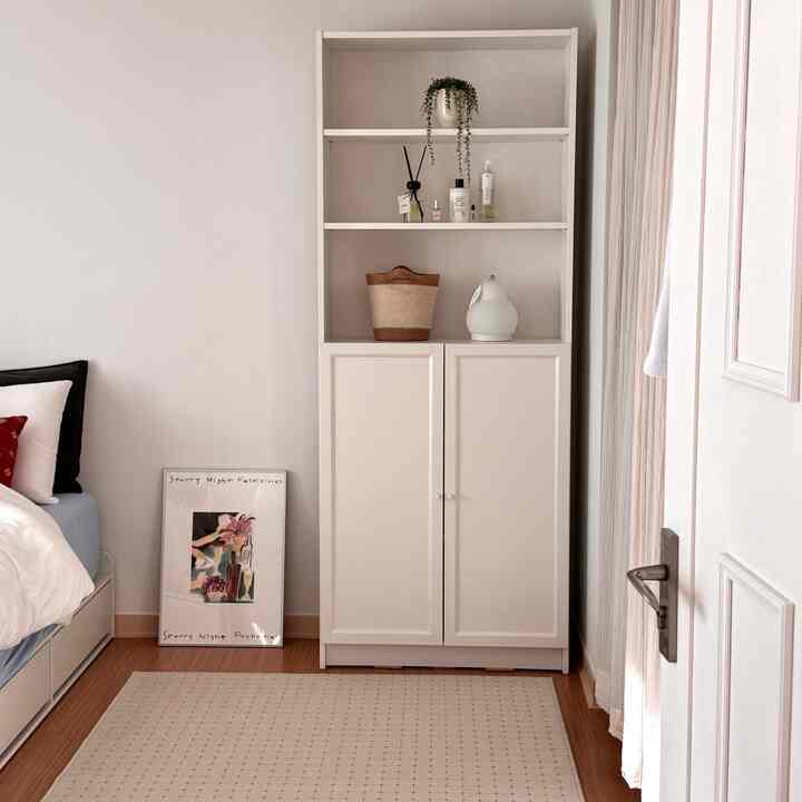A cozy and clean 6-tatami bedroom in white and wood tones featuring a bookshelf and a rug