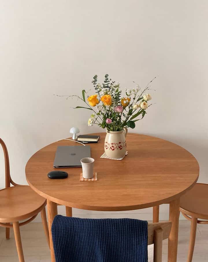 明るいアイボリーの壁と木製の丸形ダイニングテーブルが特徴の、自然な雰囲気のダイニング空間