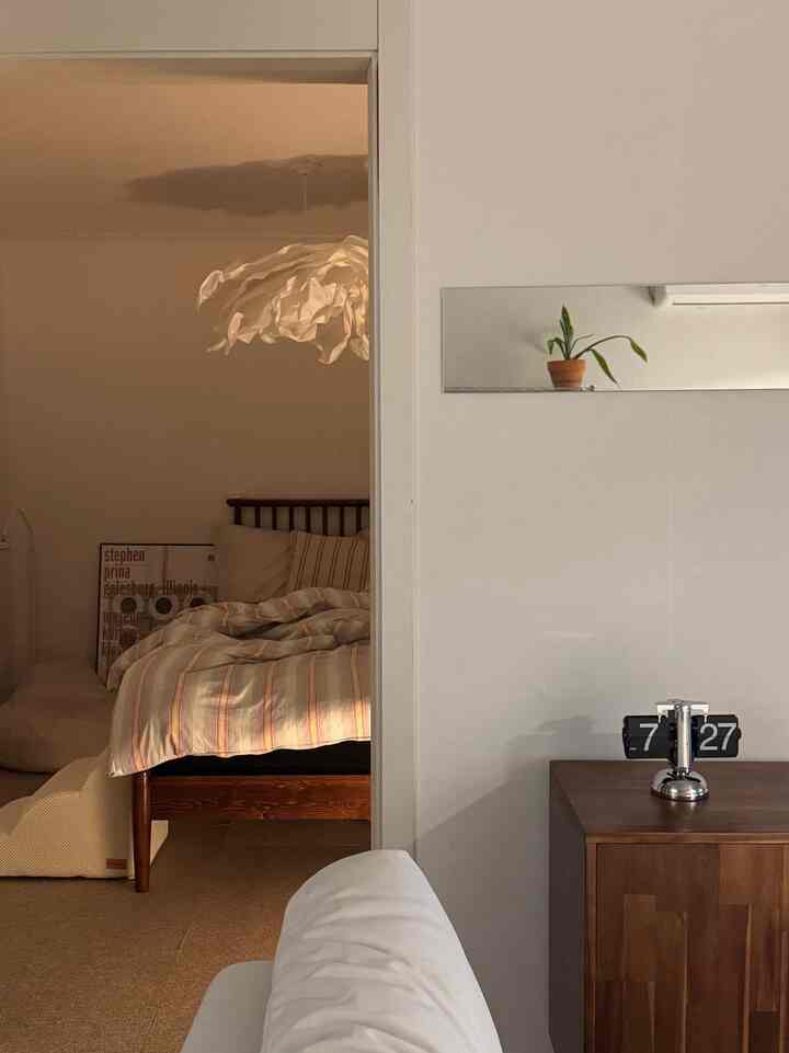 Warm beige and wood-tone natural modern living room to bedroom transition featuring sofa and pet accessories with a cozy atmosphere