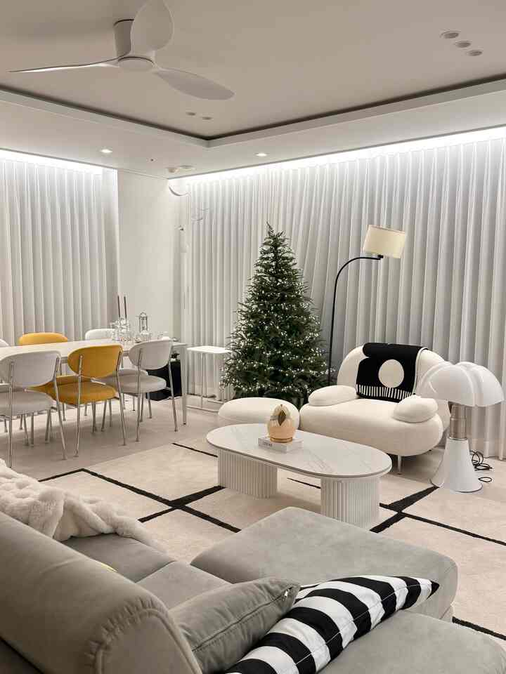 ホワイトとベージュのトーンのリビング、モダンな家具とクリスマスツリーが配置された雰囲気のあるインテリア