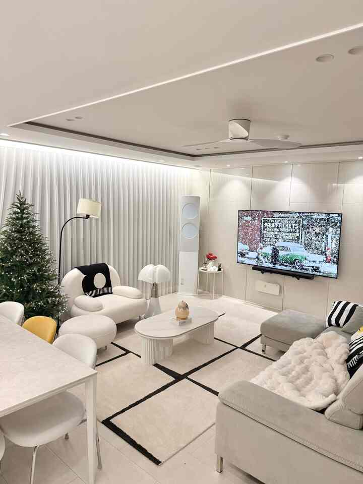 白を基調としたリビング、中央にコーヒーテーブルとソファ、左にクリスマスツリーと白いカーテンが配置されたミニマルでモダンなインテリア