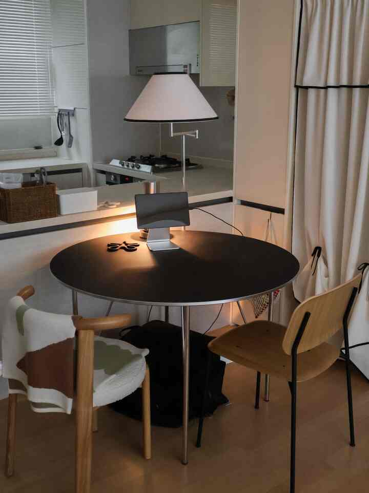 白を基調とした清潔感のあるキッチン、木目調の椅子と黒い丸テーブルが配置された二人用の空間